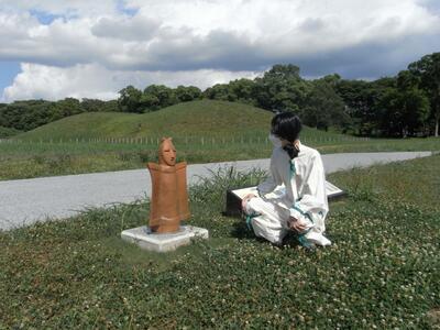 奥の山古墳の盾持人埴輪のレプリカを観察する古代人。