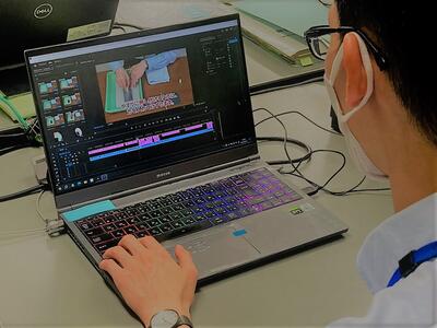 職員がパソコンで動画を編集しているところ。