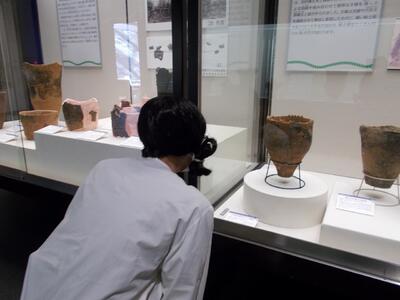 土器の文様をよく観察する古代人。