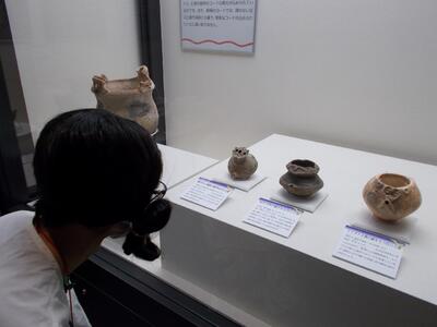 顔のついた土器３つを見比べる古代人。