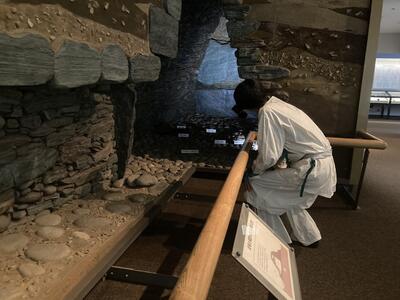 石室の再現展示を見る古代人。