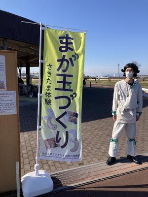 「まが玉づくり」ののぼりの横に立つ古代人。